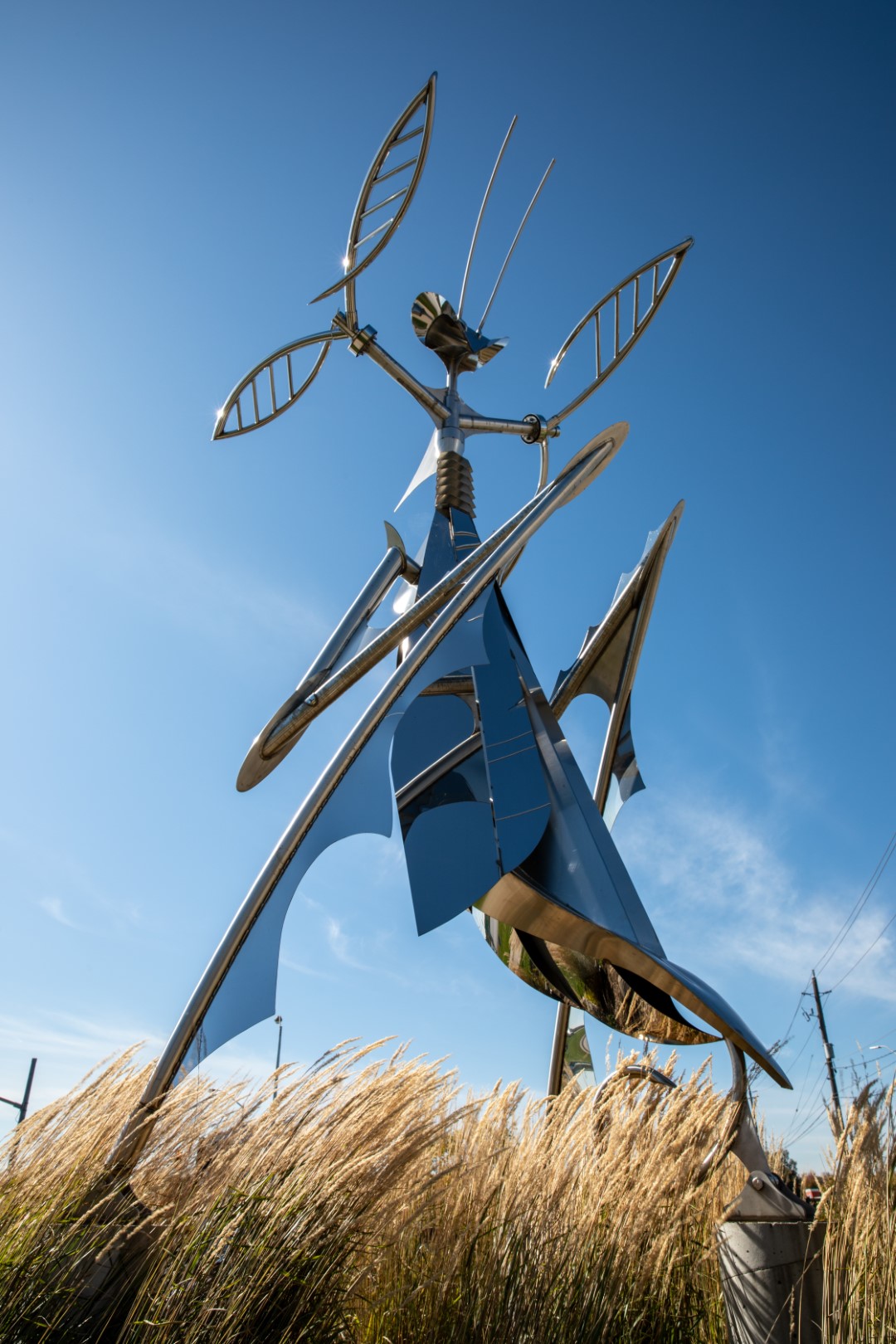 Mantis Queen sculpture standing in front of a blue sky